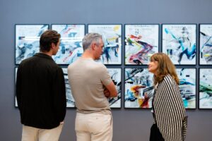 Tres personas conversando frente a obras de arte en una galería