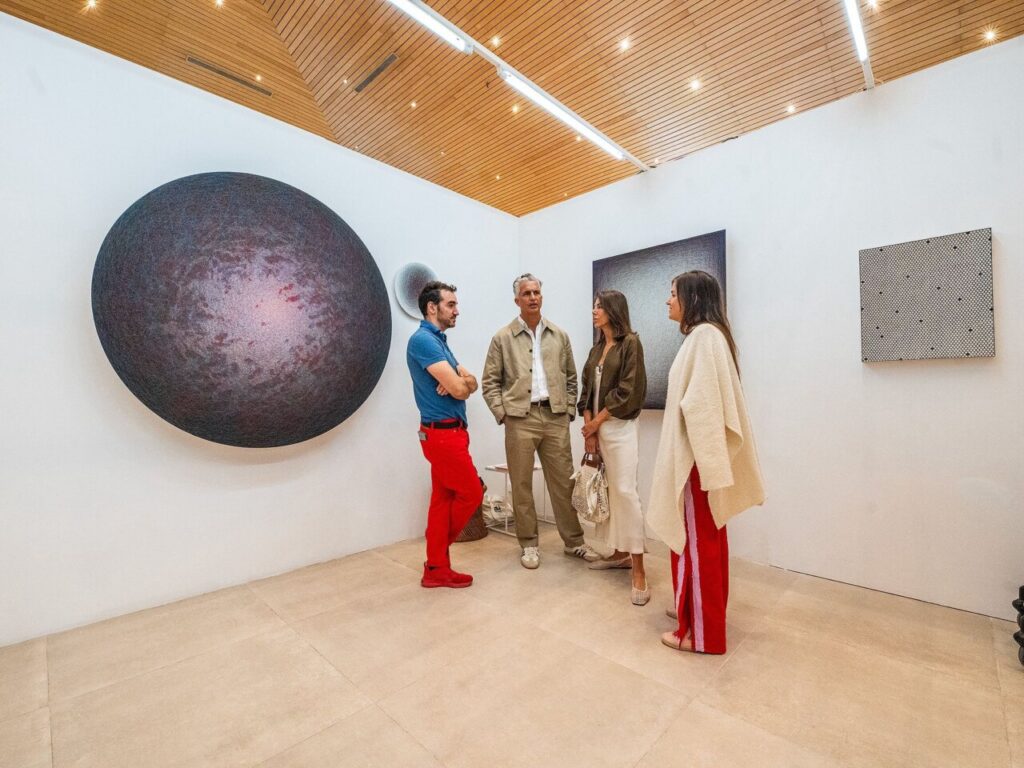 Personas conversando en una galería de arte contemporáneo.