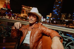Bruno Mars posando con un sombrero en un ambiente nocturno