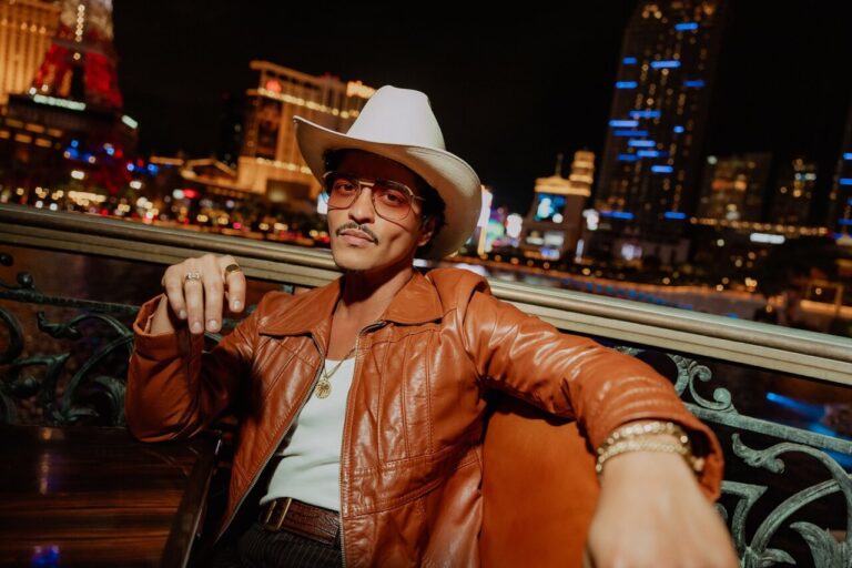 Bruno Mars posando con un sombrero en un ambiente nocturno