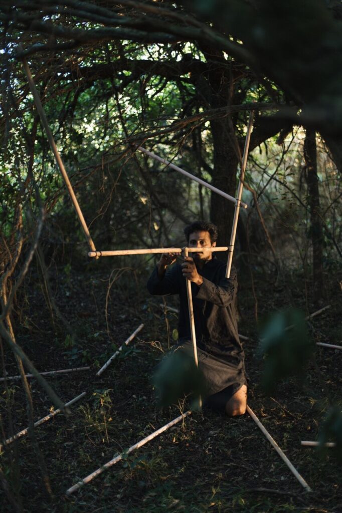 Artista trabajando en el bosque con materiales naturales y estructuras de madera
