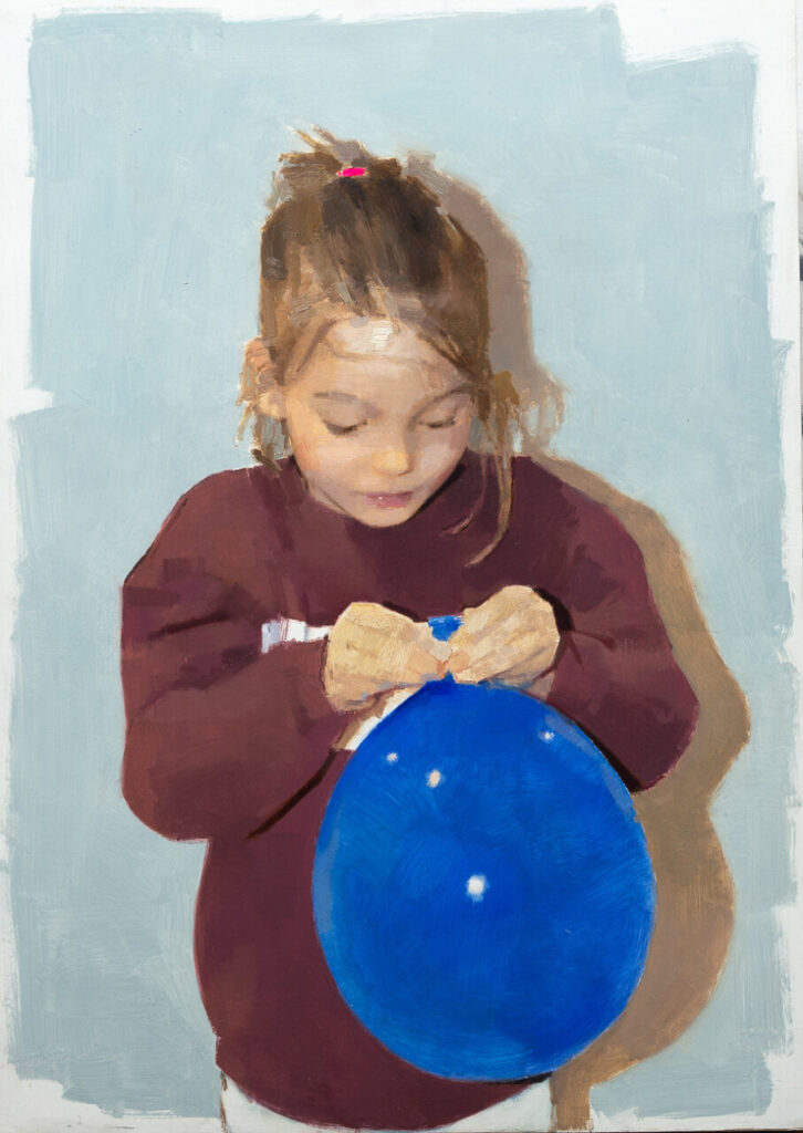 Niña sosteniendo un globo azul mientras lo ata con las manos.