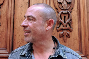 José de Divina sonriendo frente a un fondo de madera tallada