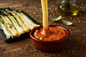 Calçots asados acompañados de salsa romesco en un plato rústico.