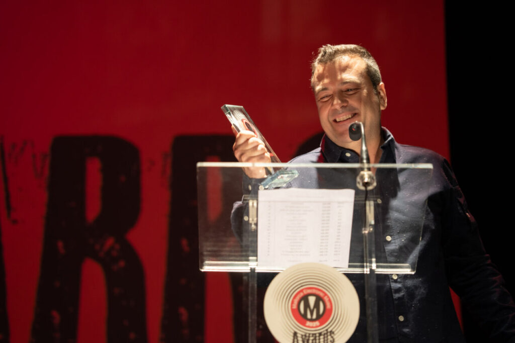 Hombre sonriente sosteniendo un premio en un podio