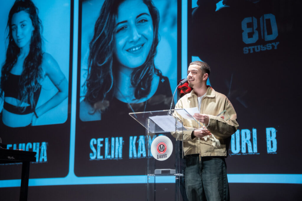Presentador en la Gala MEM Awards con fondo azul y fotos de ganadores