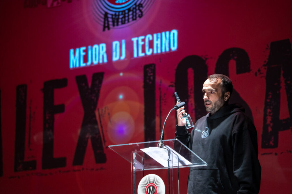 Hombre en ceremonia de premios sosteniendo un trofeo en el escenario