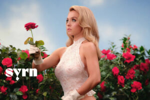 Sydney Sweeney posando con un ramo de rosas en un conjunto de lencería blanca