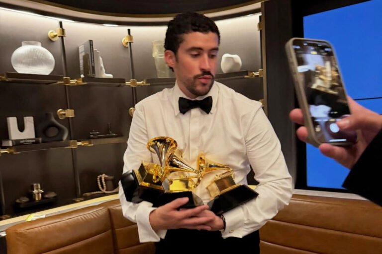 Bad Bunny sosteniendo varios premios Grammy en un evento