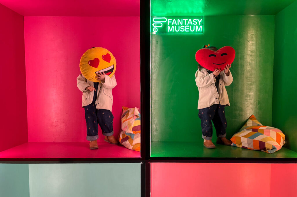 Niños en un museo con cojines de emojis en un entorno colorido