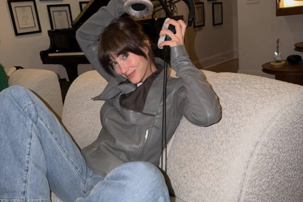 Inicio 51 Aitana Ocaña posando en un sofá con auriculares y atuendo moderno.