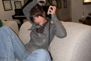 Aitana Ocaña posando en un sofá con auriculares y atuendo moderno.