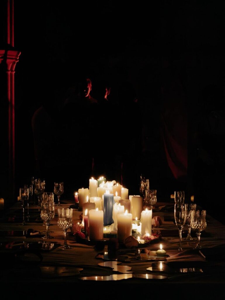 La magia de la creación: cómo Piro transforma la oscuridad en color en sus obras 3 Mesa decorada con velas de diferentes colores en un ambiente oscuro.