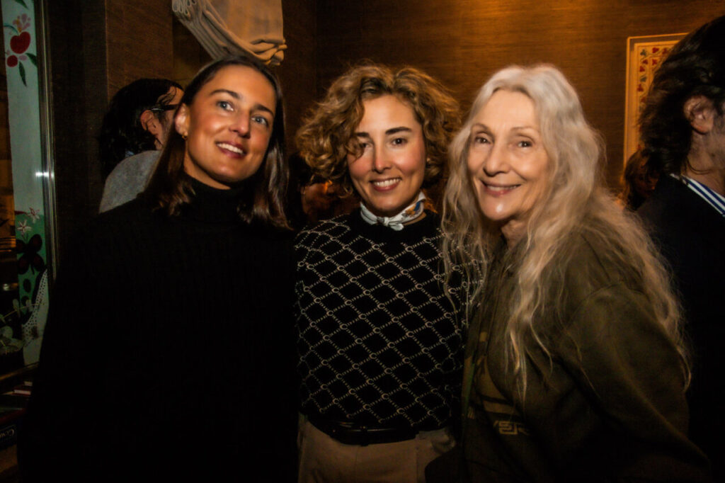 Cupa Stone X Pablo Erroz: Cuando la piedra se convierte en luz 13 Tres mujeres sonriendo en un evento social con fondo oscuro