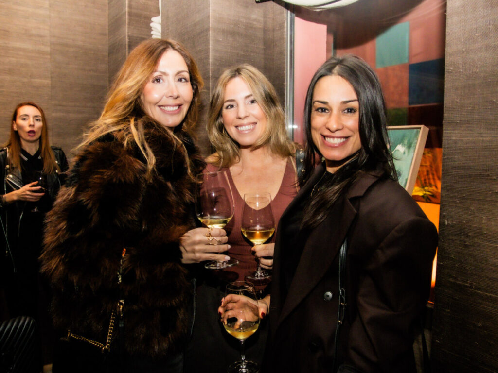 Cupa Stone X Pablo Erroz: Cuando la piedra se convierte en luz 21 Tres mujeres sonrientes sosteniendo copas de vino en una fiesta