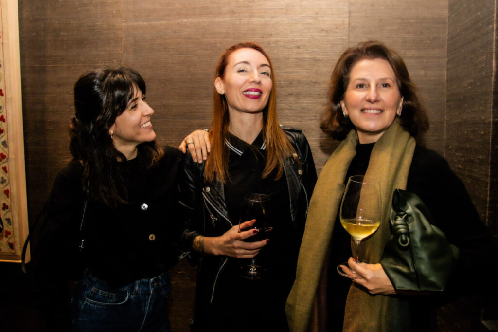 Cupa Stone X Pablo Erroz: Cuando la piedra se convierte en luz 34 Tres mujeres sonriendo en una reunión social con copas de vino