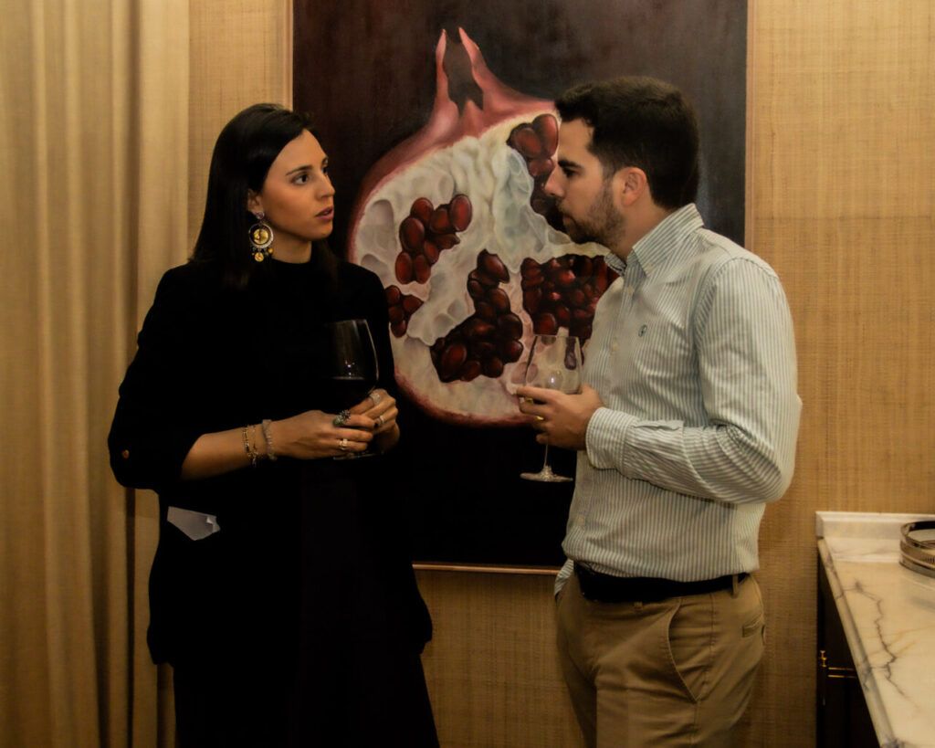 Cupa Stone X Pablo Erroz: Cuando la piedra se convierte en luz 26 Pareja conversando en un evento social con arte de granada detrás.