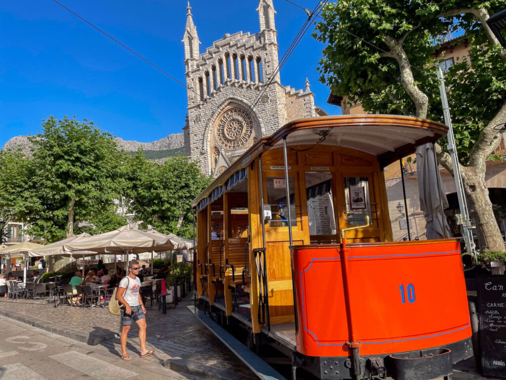 Tren de Sóller en la plaza con un edificio histórico al fondo