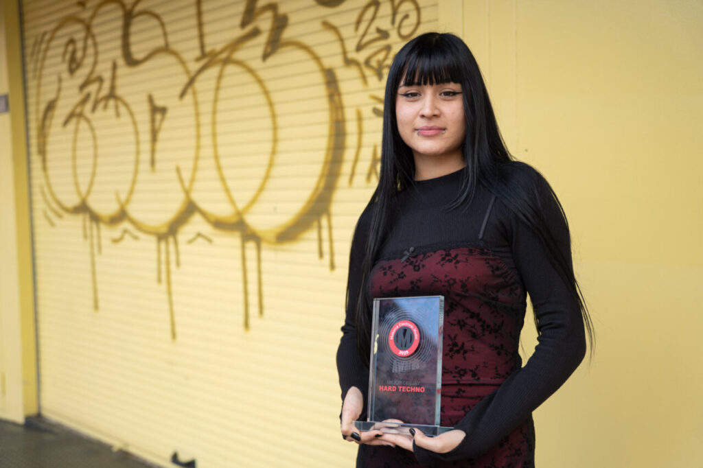 Nekita, ganadora del MEM Award a mejor deejay hard techno 2025: “Fue un momento que recordaré toda mi vida” 3 Mujer sosteniendo un premio en un fondo amarillo con graffiti
