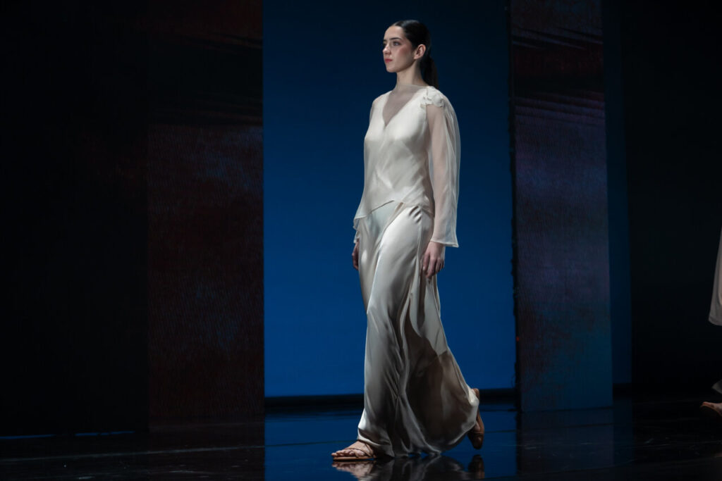Modelo caminando en pasarela con vestido de seda en desfile de moda