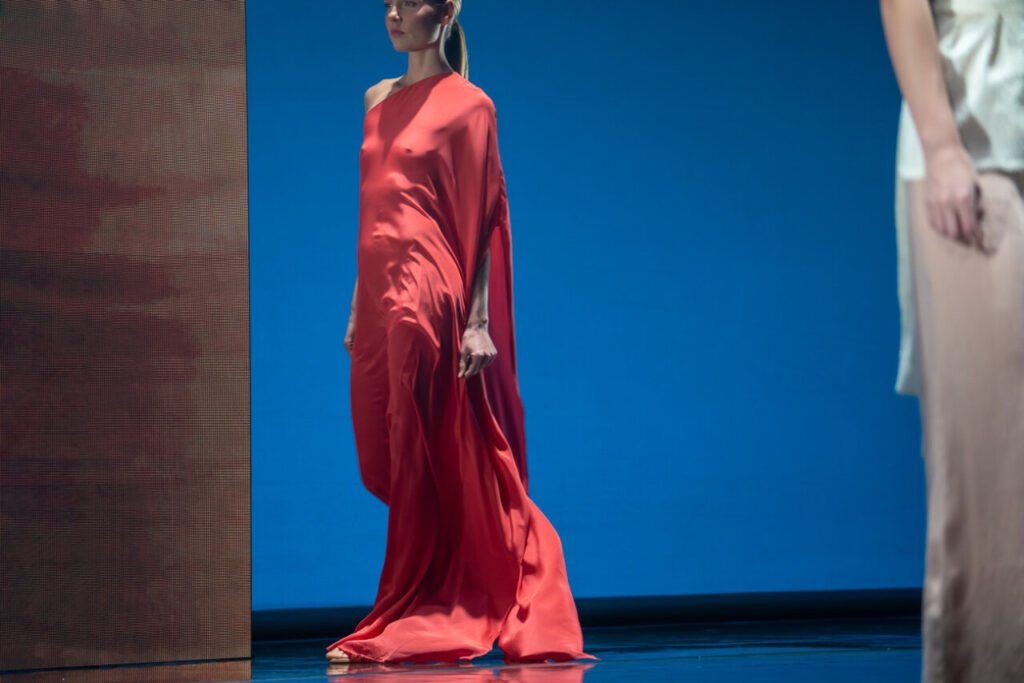 Modelo luciendo un vestido rojo en el desfile de moda artesana en Mallorca.