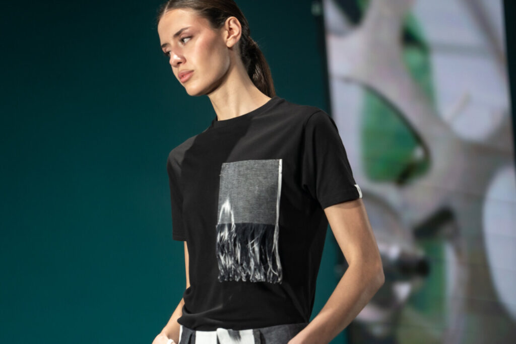 Modelo luciendo una camiseta con diseño contemporáneo en desfile de moda.