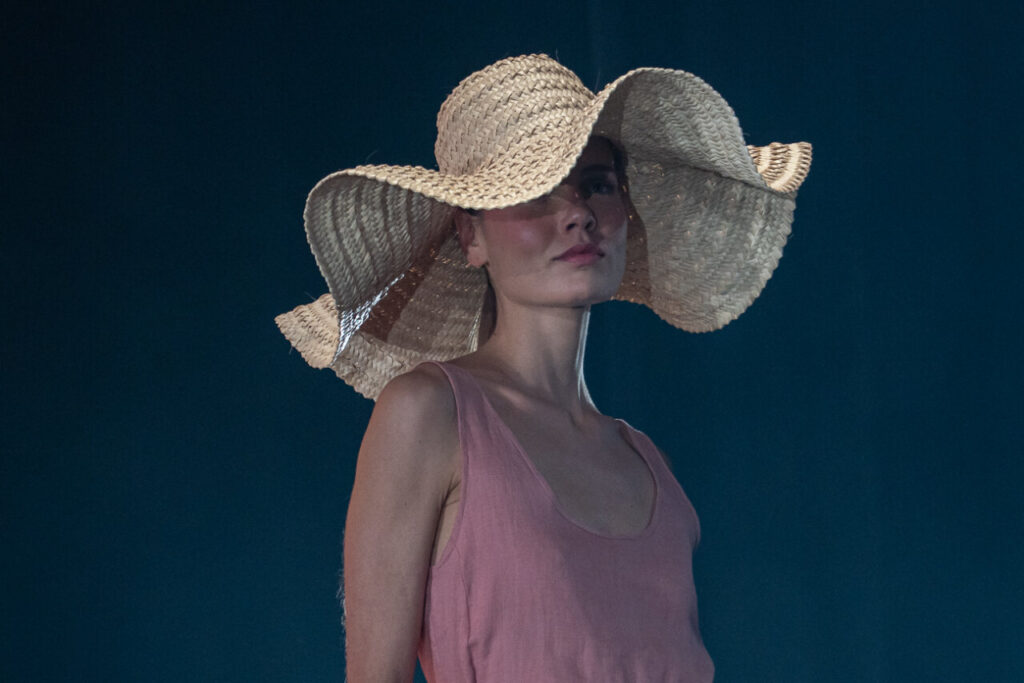 Modelo en pasarela con sombrero de paja y vestido rosa