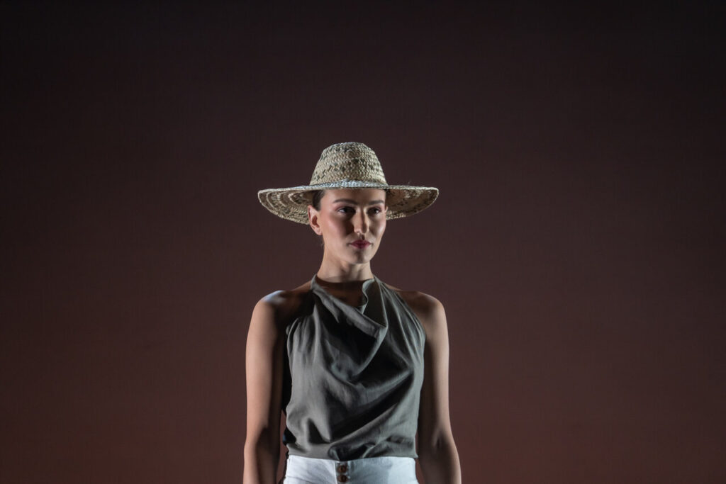 Modelo en pasarela con sombrero de paja y atuendo contemporáneo