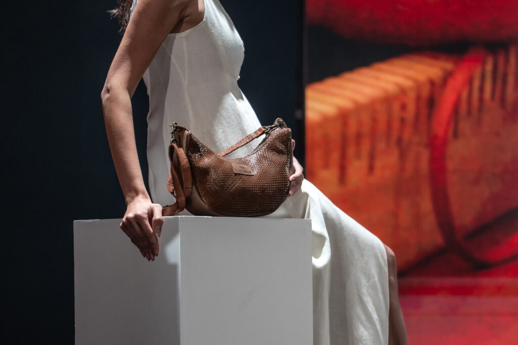 Modelo con vestido blanco y bolso de piel en pasarela de moda