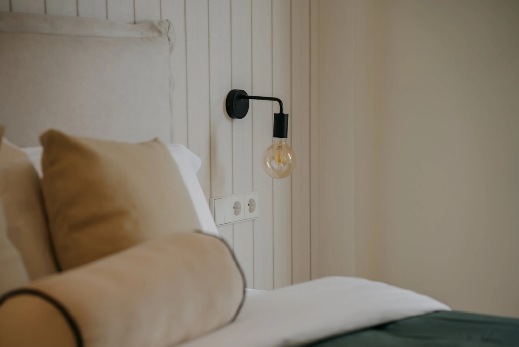 Renacer tras 50 años: La transformación de un hogar en Palma 4 Detalle de una cama con almohadas y luz moderna en la pared