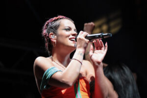 Lily Allen cantando en un concierto con un micrófono en mano