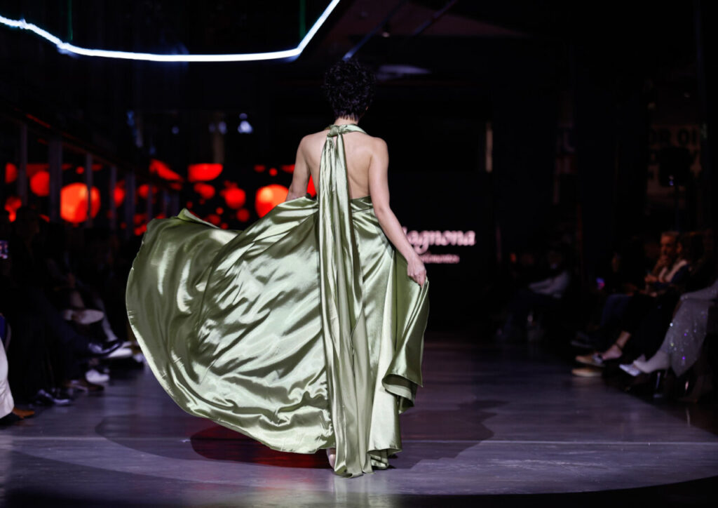 Modelo en pasarela con vestido largo de seda verde en evento nupcial