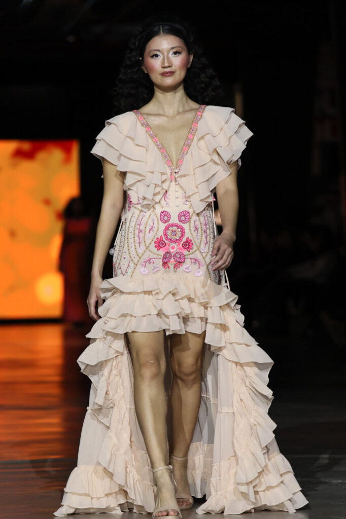 Modelo en pasarela con vestido nupcial de volantes y bordados coloridos.