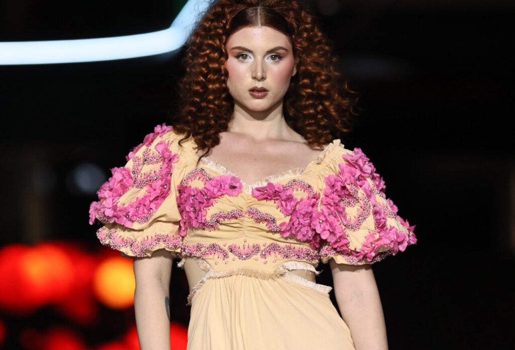 Modelo en pasarela con vestido nupcial color amarillo y detalles florales rosas