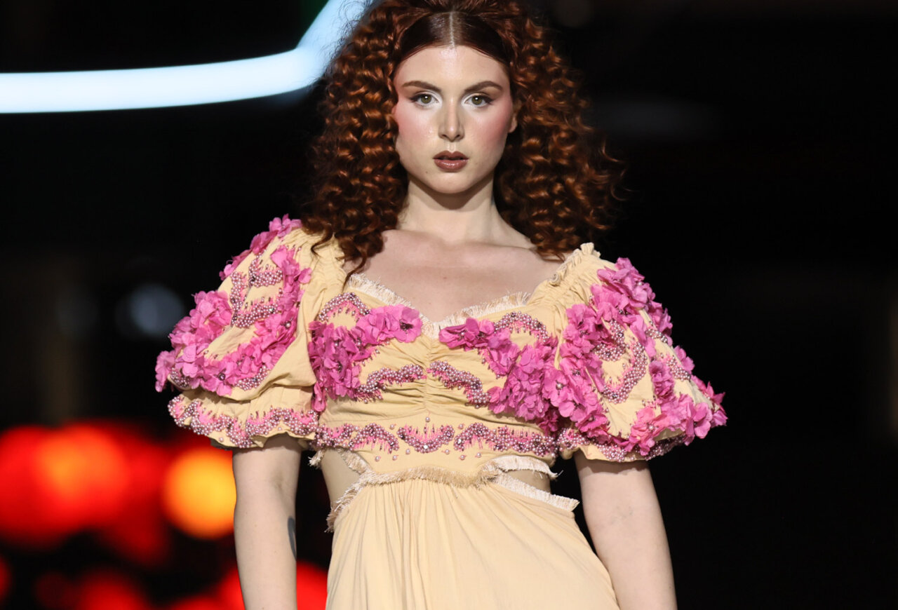 Modelo en pasarela con vestido nupcial color amarillo y detalles florales rosas