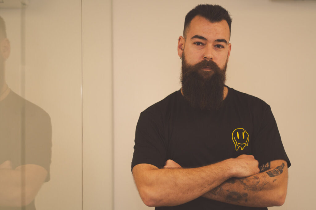 Retrato de un hombre con barba y camiseta negra en un entorno moderno