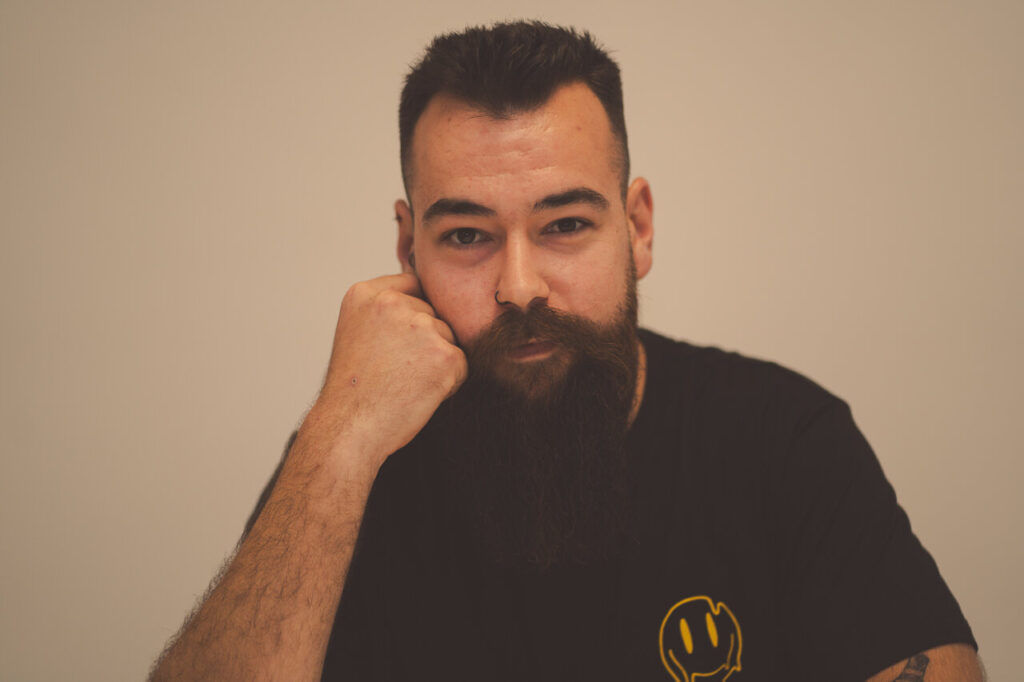 Retrato de un hombre con barba y camiseta negra, pensativo.