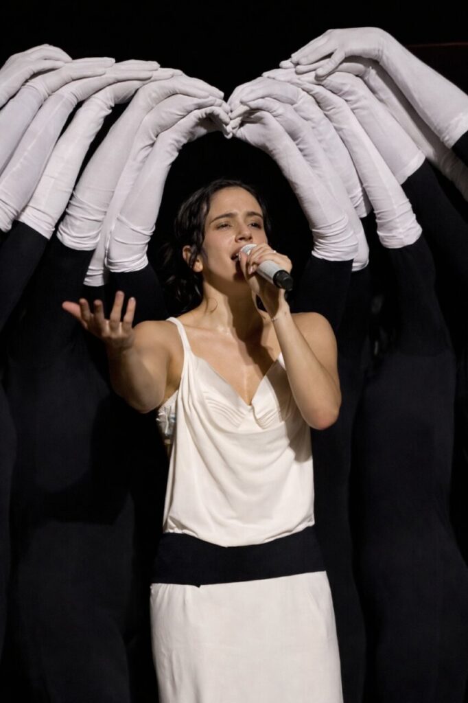 Rosalía actuando en el LUX Tour en Lyon con manos de fondo.
