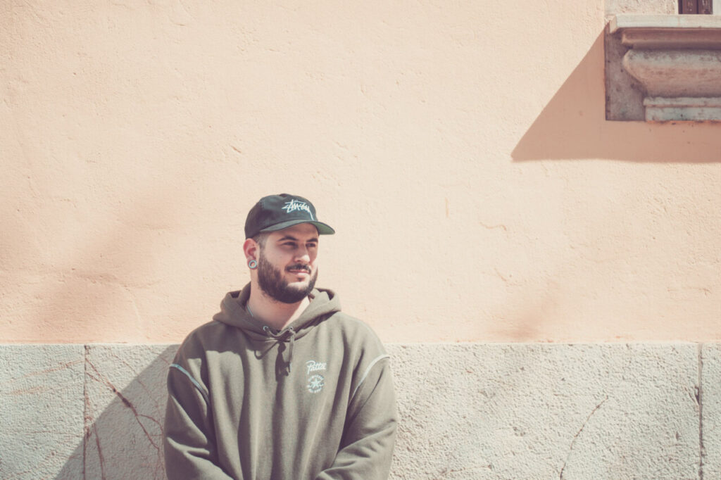 Hombre con gorra y sudadera en pared de color claro