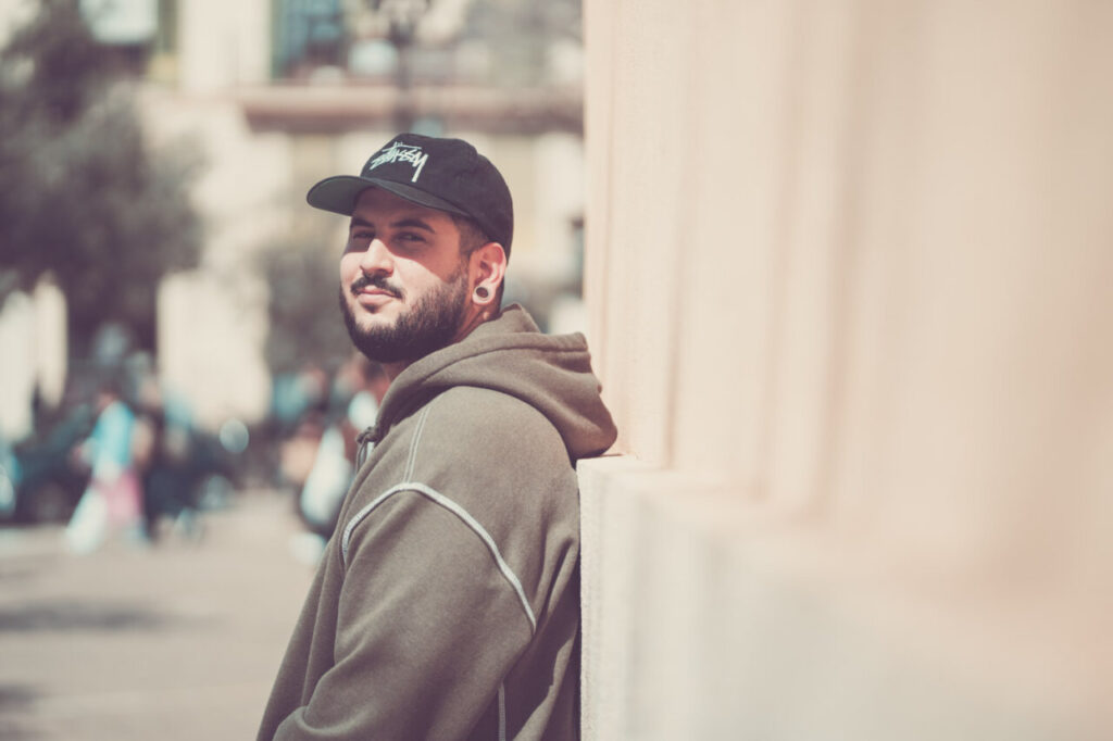 Hombre con gorra y sudadera posando en la calle