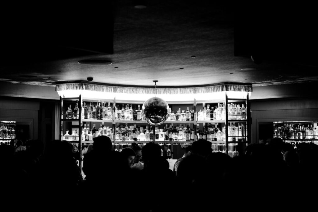 Bar con botellas iluminadas y gente en un evento de moda