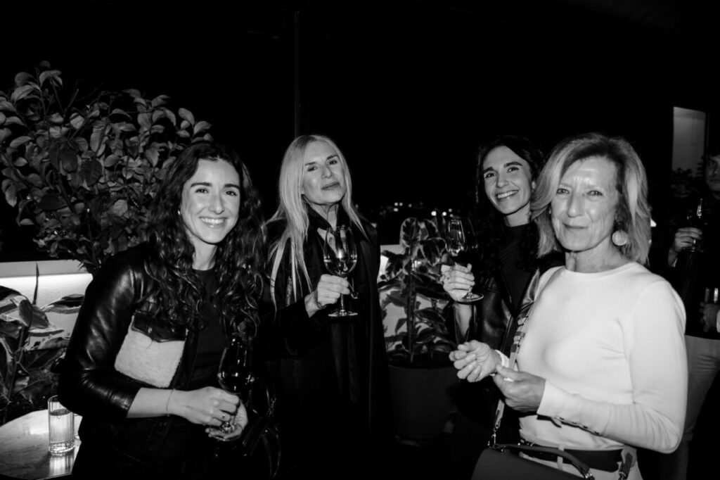 Cuatro mujeres sonrientes en una celebración con copas en mano