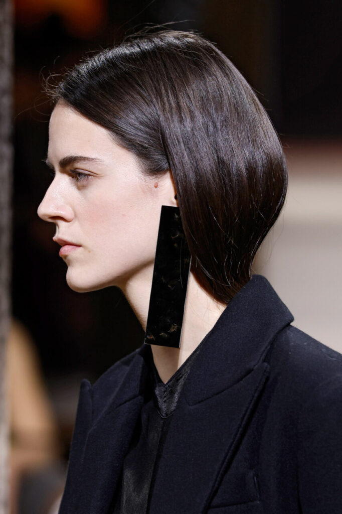 Modelo con pendientes grandes y cabello lacio en desfile de moda