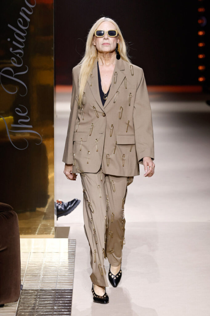 Modelo luciendo un traje beige con imperdibles en la pasarela de MBFWM