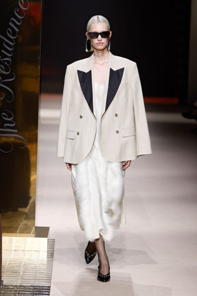 Modelo en pasarela con blazer beige y vestido blanco en MBFWM