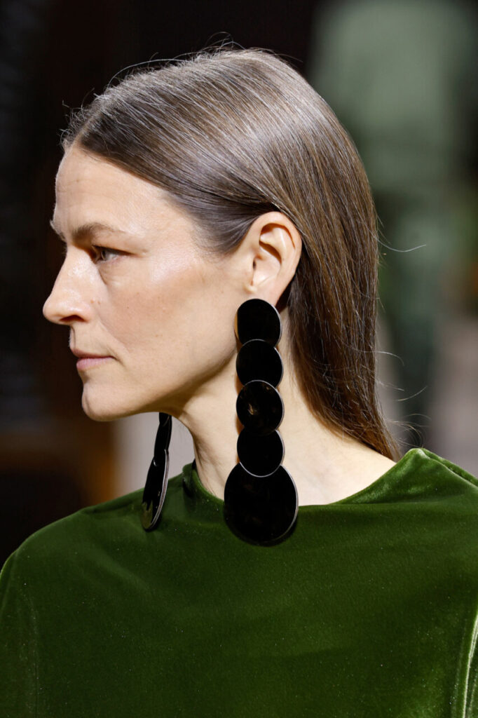 Modelo con pendientes grandes y blusa verde en desfile de Pablo Erroz