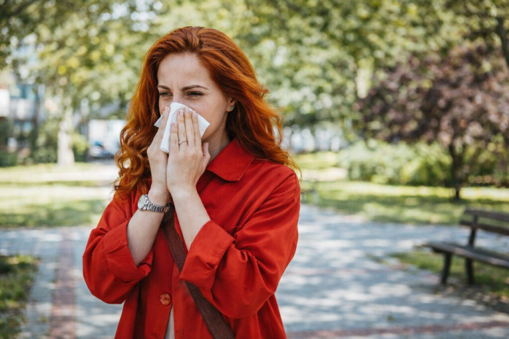 Mujer con cabello rojo usando un pañuelo en un parque durante la primavera