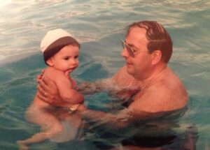 Un niño pequeño en brazos de un hombre en una piscina