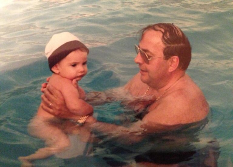 Un niño pequeño en brazos de un hombre en una piscina