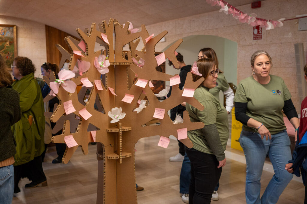 Personas participando en una actividad comunitaria con un árbol de cartón